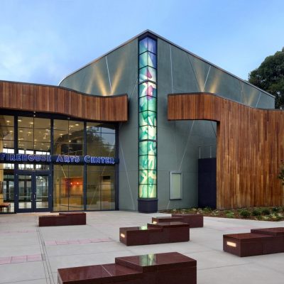 Modern event center with glass windows and seating area outside the Firehouse Arts Center in Pleasanton.